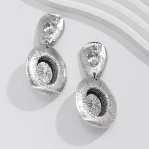Close-up of vintage silver hat-shaped metal earrings with textured finish