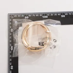 Gedetailleerde weergave van goudkleurige metalen druppelarmband met meetlint