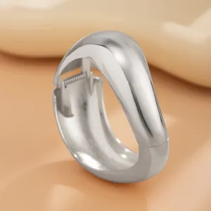 Close-up van een zilver gepolijste metalen armband met een uniek waterdruppel ontwerp.