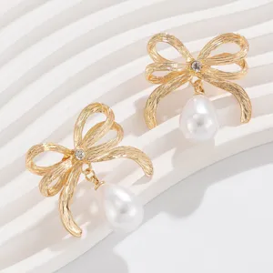 Nahaufnahme von eleganten goldenen Schleifenohrringen mit Tropfenperlen und Kristallen