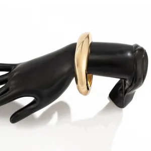 Glanzende gouden druppelvormige metalen armband op een zwarte mannequinhand.