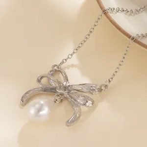 Detailaufnahme einer eleganten silbernen Schleifenkette mit einer weißen Perle.