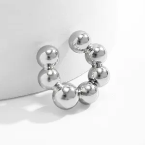 Dettaglio ravvicinato di un ear cuff a sfere metalliche argento lucido per donna.