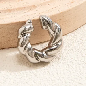 Dettaglio di un ear cuff a spirale argento senza buco su sfondo in legno naturale e sabbia