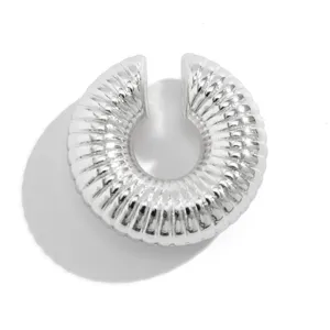 Dettaglio macro di un earcuff color argento con elegante trama a spirale metallica