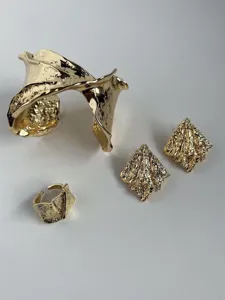 Vista detallada del conjunto de joyas doradas con brazalete, pendientes y anillo.