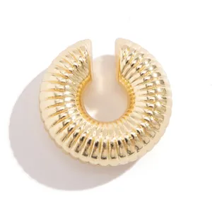 Primo piano di un ear cuff circolare dorato con un design unico a trama a spirale