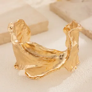 Vista detallada de brazalete dorado irregular plisado con textura metálica única