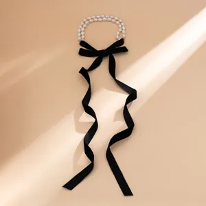 Elegant close-up of a vintage long black velvet bow choker necklace with white pearls