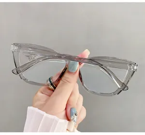 Close-up of stylish grey cat-eye glasses with anti-blue light coating held by hand.