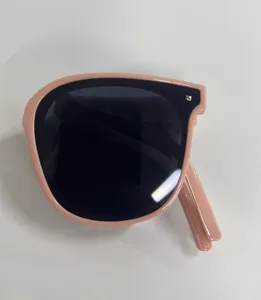 Detail view of stylish pink folding sunglasses with dark lenses for UV protection