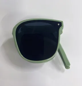 Close-up view of foldable green sunglasses with dark lenses in a compact folded state
