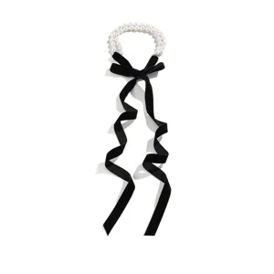 Macro view of long black velvet ribbon choker with elegant white pearl bead detailing.