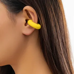 Dettaglio di un ear cuff giallo a coste che mostra la trama e la vestibilità.