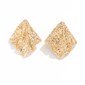 Primer plano de pendientes de metal arrugado irregular dorado con textura vintage chic.