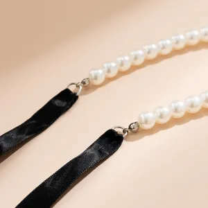 Close-up of white pearl necklace with black ribbon tie and silver-tone hardware