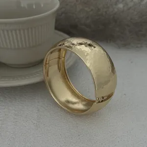 Nahaufnahme eines eleganten goldenen Armreifs mit Hammerschlag-Textur und Verschluss