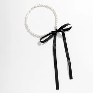 Detail of vintage pearl necklace featuring elegant black ribbon bow tie