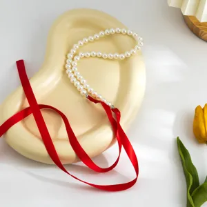 Detailed view of vintage pearl choker with elegant long red velvet ribbon tie closure