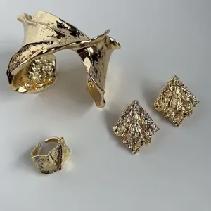 Conjunto de joyas doradas con brazalete plisado, pendientes y anillo abierto