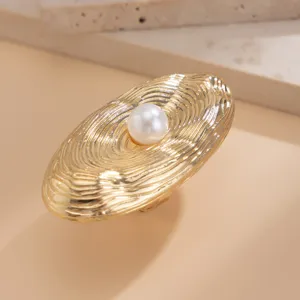 Detailed macro view of an irregular gold ripple ring featuring a central white pearl