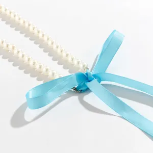 Close-up detail of white pearl necklace with a vibrant blue ribbon bow tie