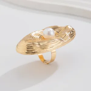 Detailed macro shot of an irregular golden alloy ring with wave texture and a pearl accent.