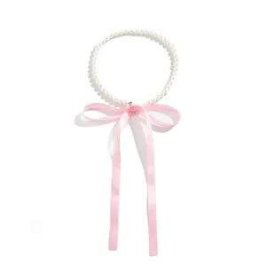 Detail of an elegant white pearl choker necklace with a long pink satin ribbon bow.