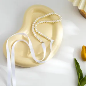 Close-up of retro long pearl necklace with elegant white ribbon ties for DIY bows