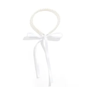 Detailed view of elegant white pearl necklace with large silk ribbon bow tie