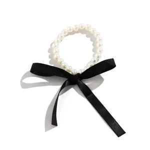 Close-up detail of a vintage pearl choker necklace with a long black satin ribbon bow
