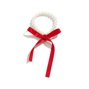 Detailed view of white pearl choker necklace with long red silk ribbon bow