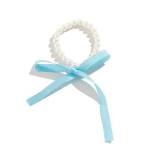 Close-up of retro white pearl necklace with long light blue silk ribbon bow