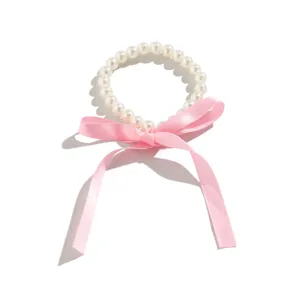 Close-up detail of a vintage style pearl choker necklace with a soft pink ribbon bow