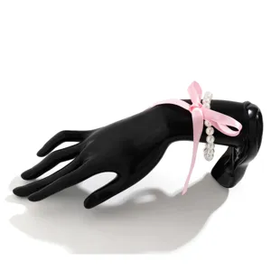 Detailed macro view of vintage pink ribbon bow and white pearl necklace on a hand model