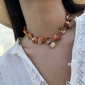 Detaillierte Nahaufnahme einer braunen Muschelkette mit goldenem Anhänger am Modell
