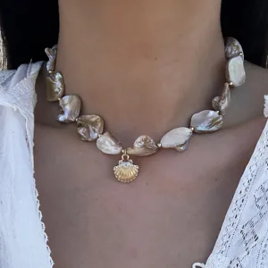 Nahaufnahme einer unregelmäßigen Muschelkette im Meeresstil mit goldenem Anhänger