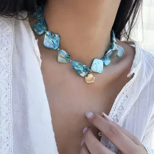 Detailansicht der Halskette im Ozeanstil mit blauen Muscheln und Goldanhänger am Modell