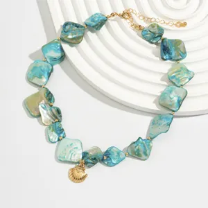 Detailansicht einer blauen Muschelkette mit unregelmäßigen Elementen und Goldanhänger