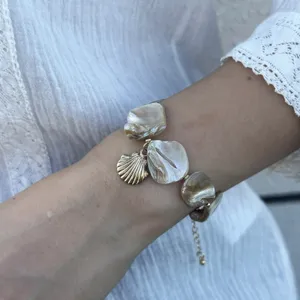 Detailansicht eines Armbands aus echten Muschelstücken mit goldenem Muschelanhänger