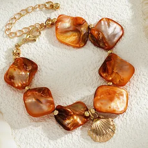 Nahaufnahme von Schmuck im Meeresstil mit orangen Muschelstücken und Goldmuschel-Anhänger
