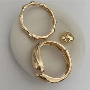 Detailed view of polished gold waterdrop-shaped and bamboo-textured metal bangles
