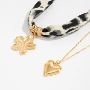 Detailed view of leopard print silk scarf necklace with gold heart and flower pendant