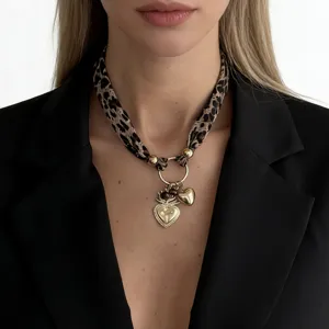 Detailed view of leopard print scarf necklace with gold heart-shaped charms on model