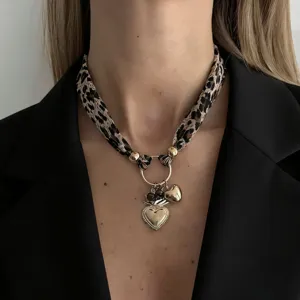 Detailed macro shot of a leopard print silk scarf necklace with golden heart pendants.