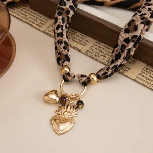 Detail showing vintage leopard print scarf necklace with golden lava heart pendant