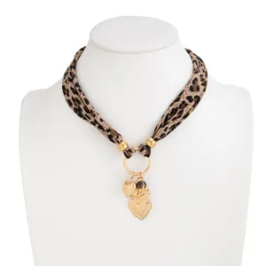 Detailed view of leopard print silk scarf necklace with vintage gold heart charms