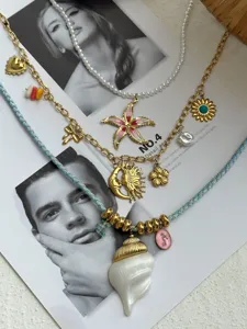 Detail of layered necklaces with shell, starfish, and sun charms on a vintage background.
