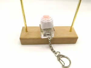 Close-up view of a cute pink cat paw mechanical switch keycap light-up keychain toy