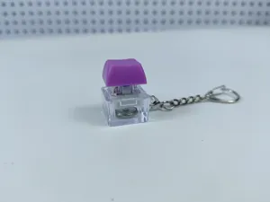 Mechanical keyboard switch keychain detail view showing clear housing and glowing purple cap.